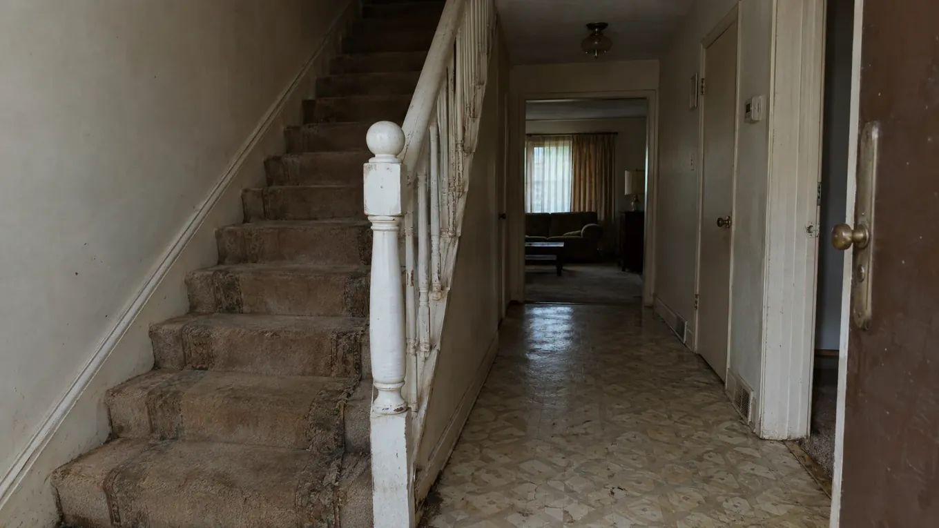 Worn Entry and Stairs Before | Music City Floor Entryway with worn brown carpet on the staircase, patterned tan linoleum flooring and chipped white railings