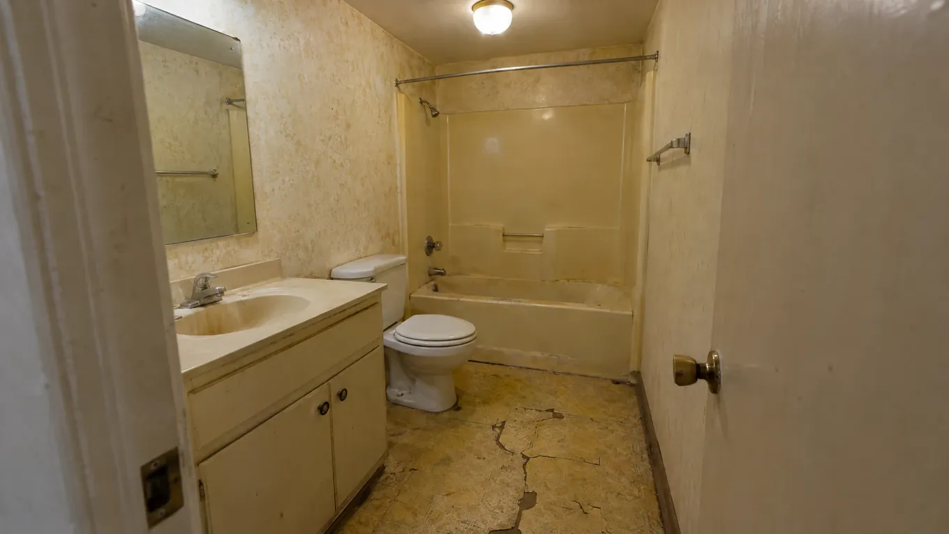 Cracked Linoleum Bathroom Before | Music City Floor Outdated bathroom with cracked yellow linoleum flooring, a laminate vanity and an acrylic bathtub