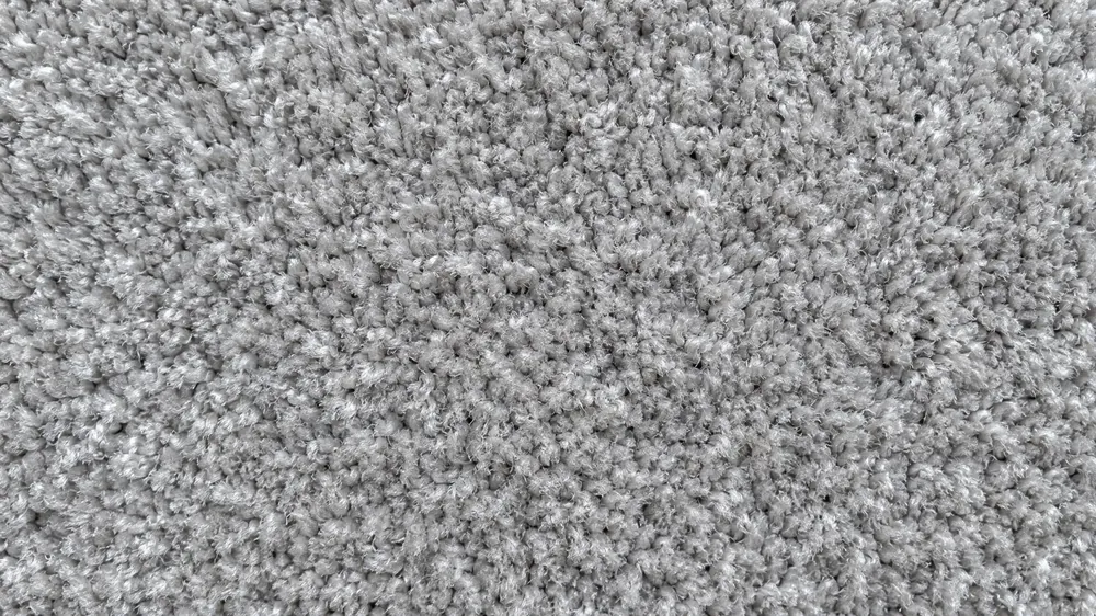 Close-up of dense, twisted gray carpet fibers with soft shadow depth